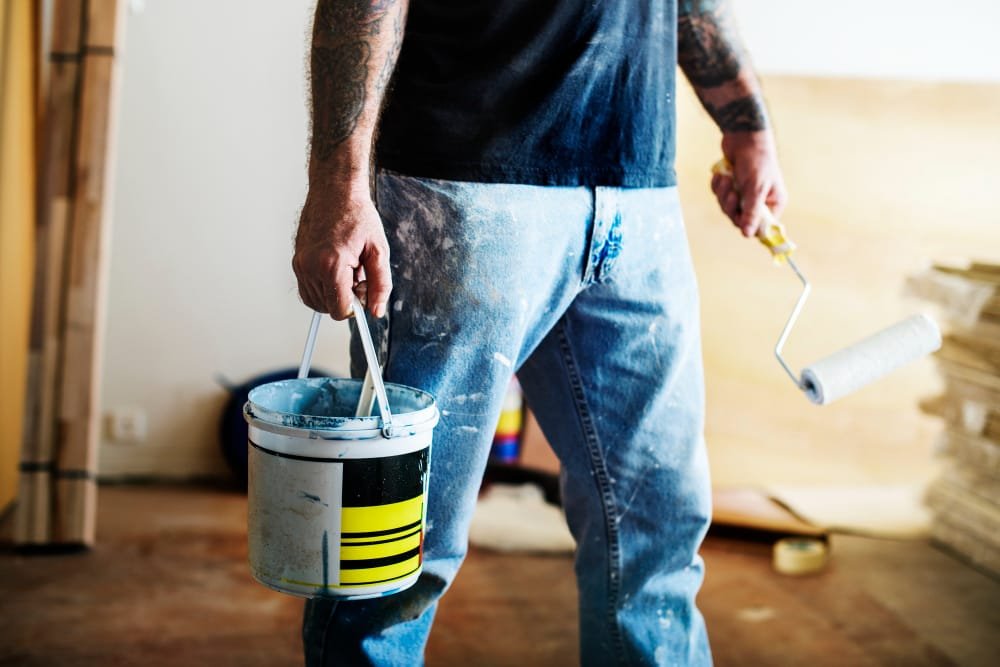 Man walking with paint can and roller wearing jeans and t shirt.jpg